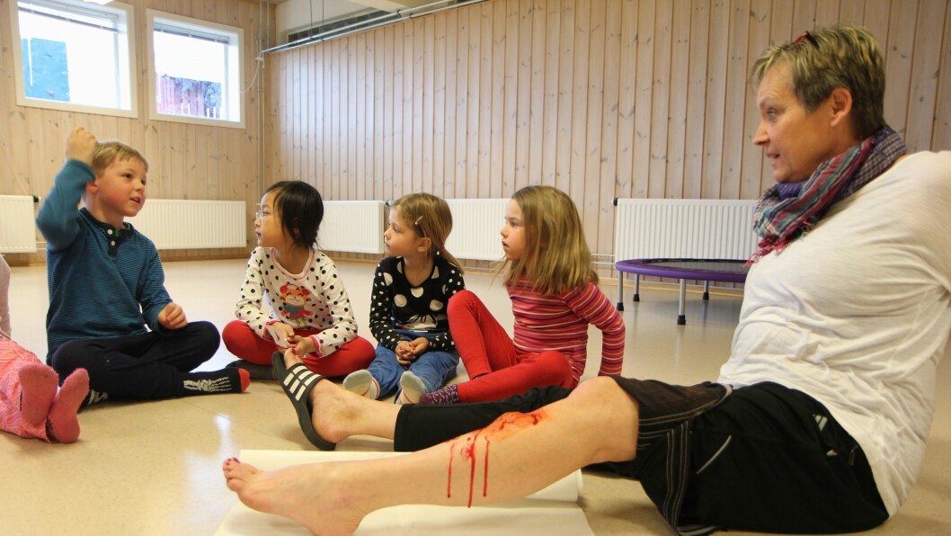 Jorunn Johansen viser barna i Holmejordet barnehage hvordan man kan lappe sammen et kutt i kneet.