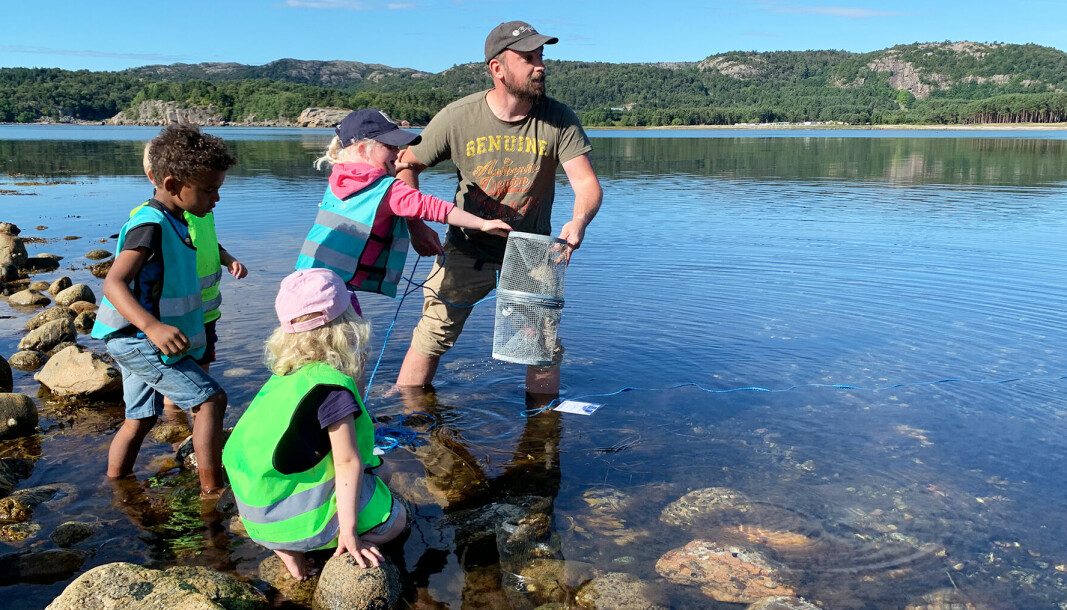 Fagarbeider Kjetil Windsland og barna sjekker om det har kommet krabber i teinene de fikk fra Havforskningsinstituttet.